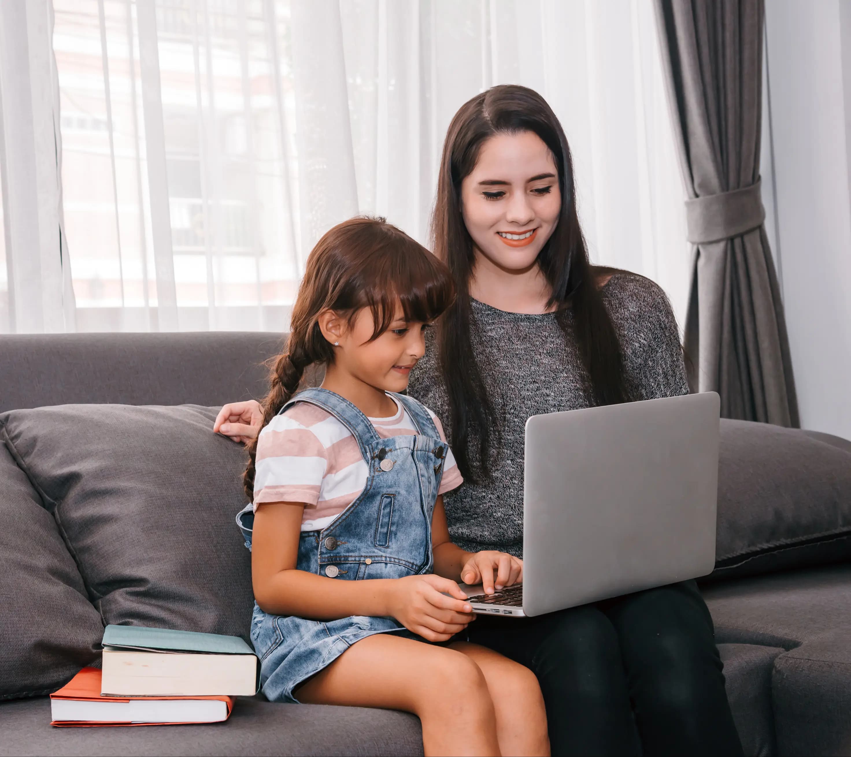 Mother and daughter utilizing a laptop comfortably on a sofa